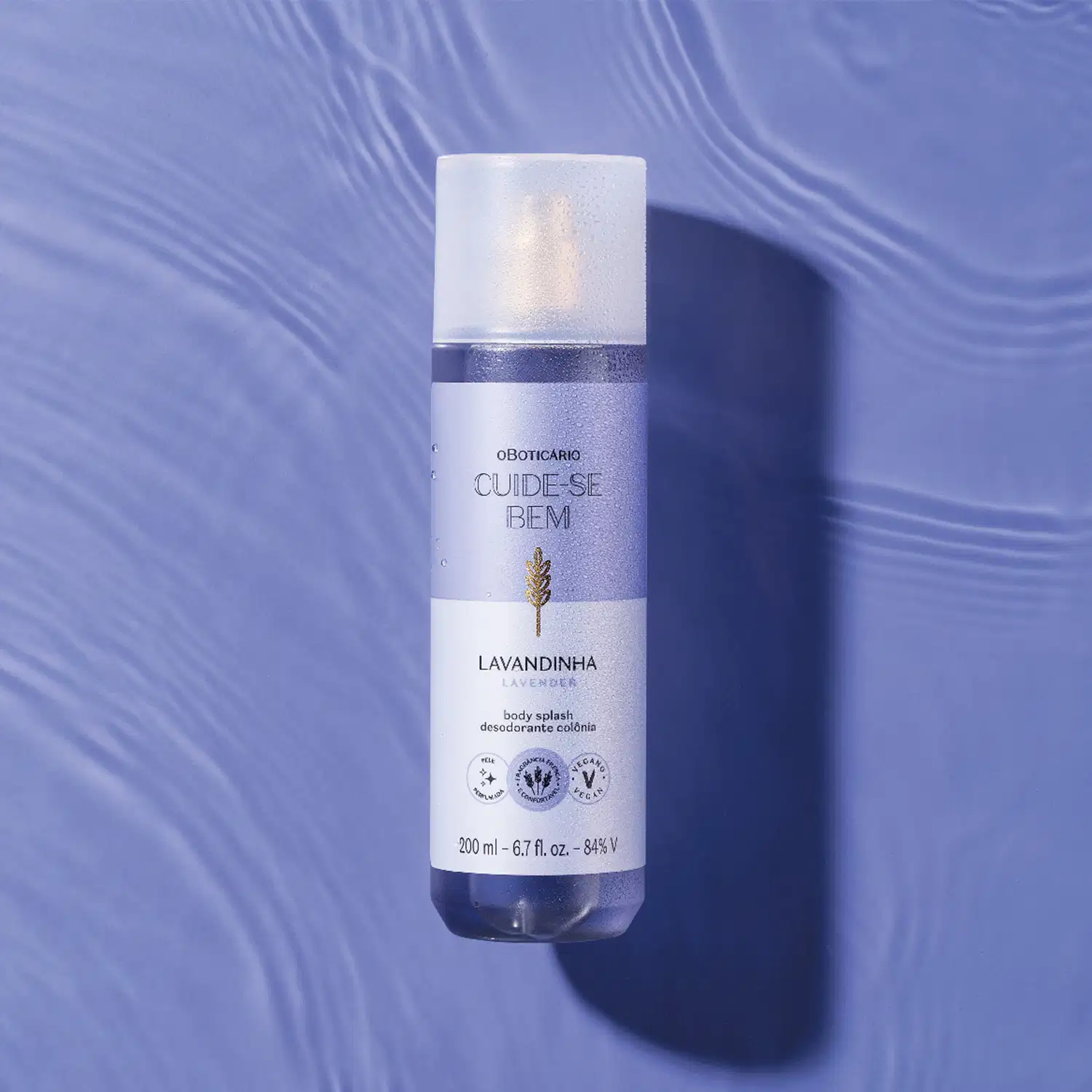 Frasco branco de item de perfumaria da marca Cuide-se bem, com rótulo roxo e dourado, sobre superfície azul com reflexos ondulados.