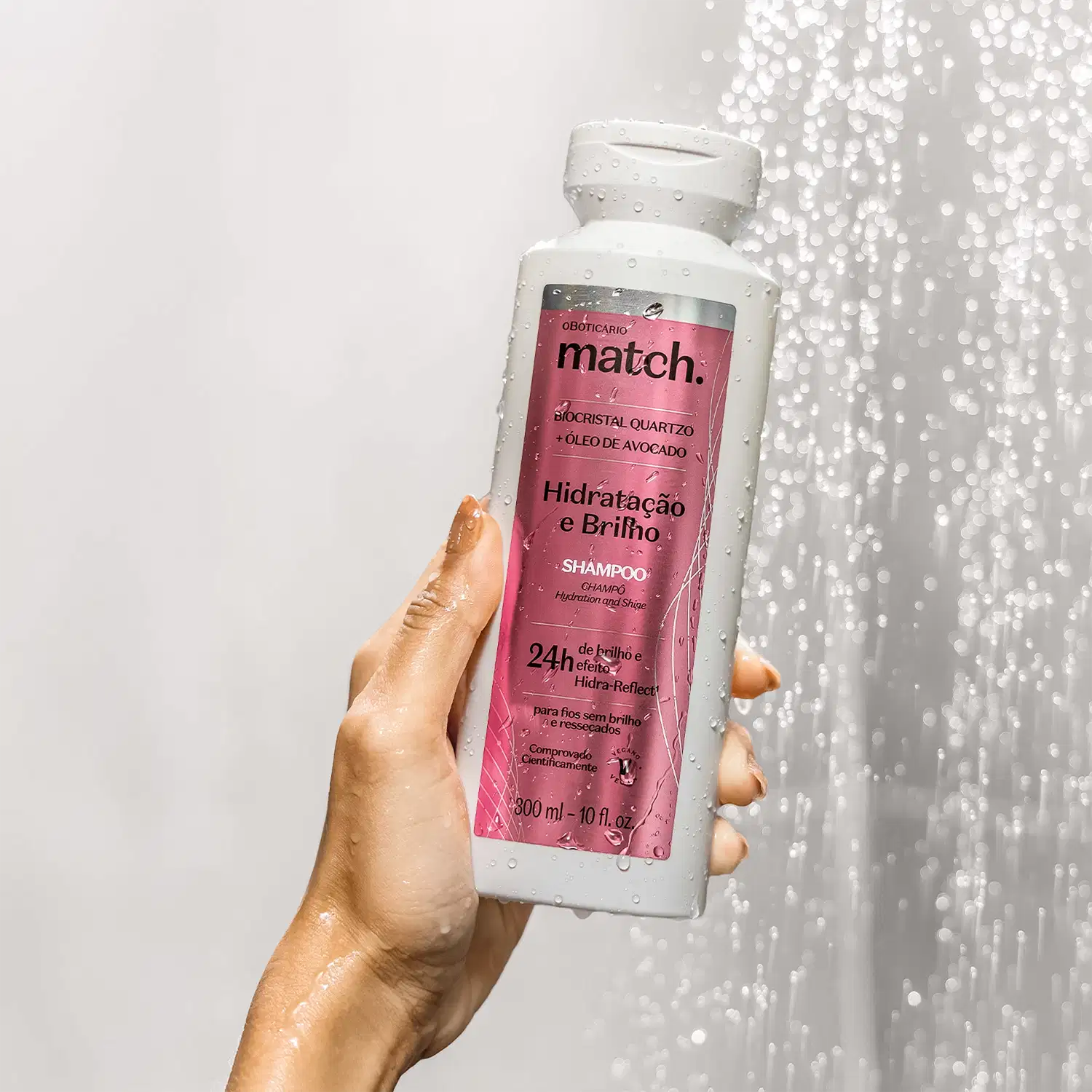 Ambiente de banheiro com fundo claro e brilhante, destacando um frasco rosa da linha Match. O produto é um shampoo para hidratação e brilho dos cabelos, com informações sobre sua composição e benefícios.