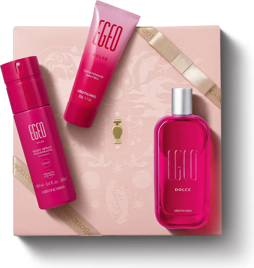 Caixa rosa claro com padrão floral em dourado e três itens de perfumaria da marca Egeo Dolce sobre ela, sendo: frasco de desodorante colônia, tubo de body spray e bisnaga de creme hidratante desodorante, todos na cor pink.