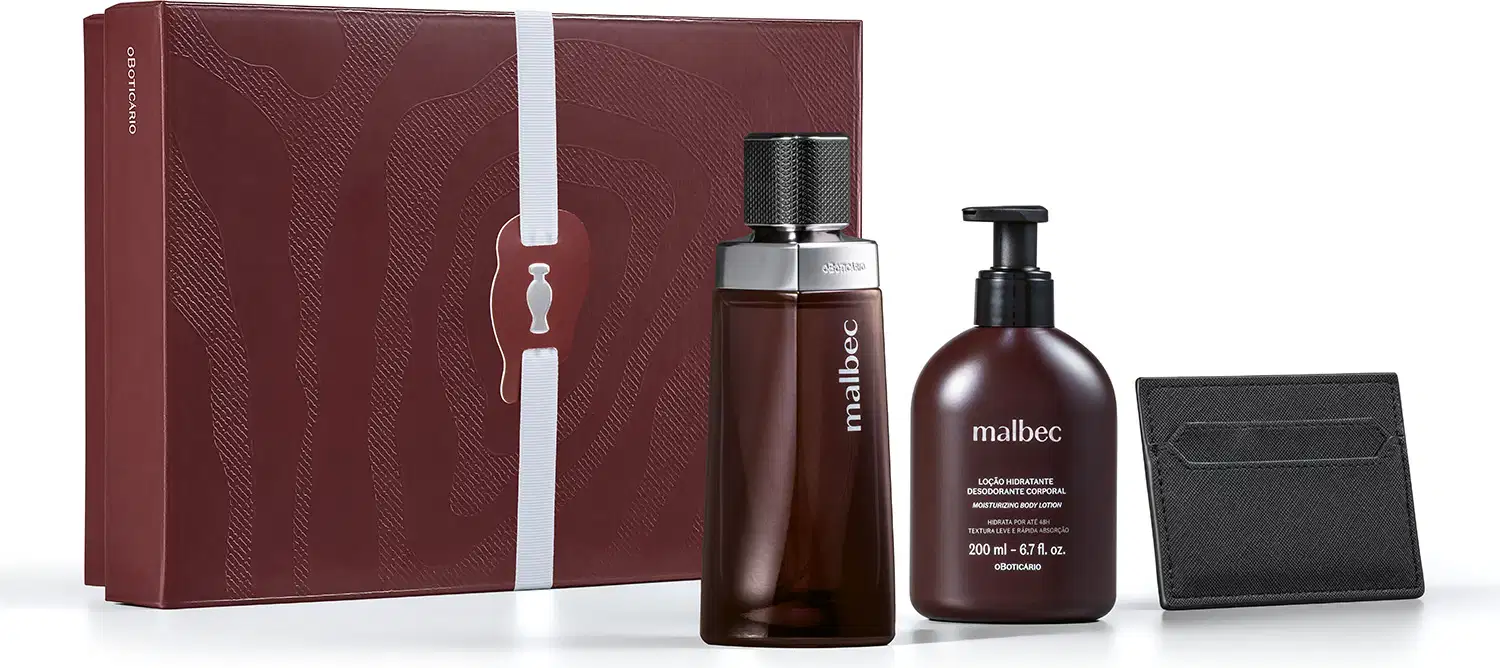 Caixa de presente marrom com padrão de raíz de árvore, contendo frasco de item de perfumaria Malbec de 200 ml e bisnaga de 200 ml da mesma marca, acompanhados de uma carteira preta.