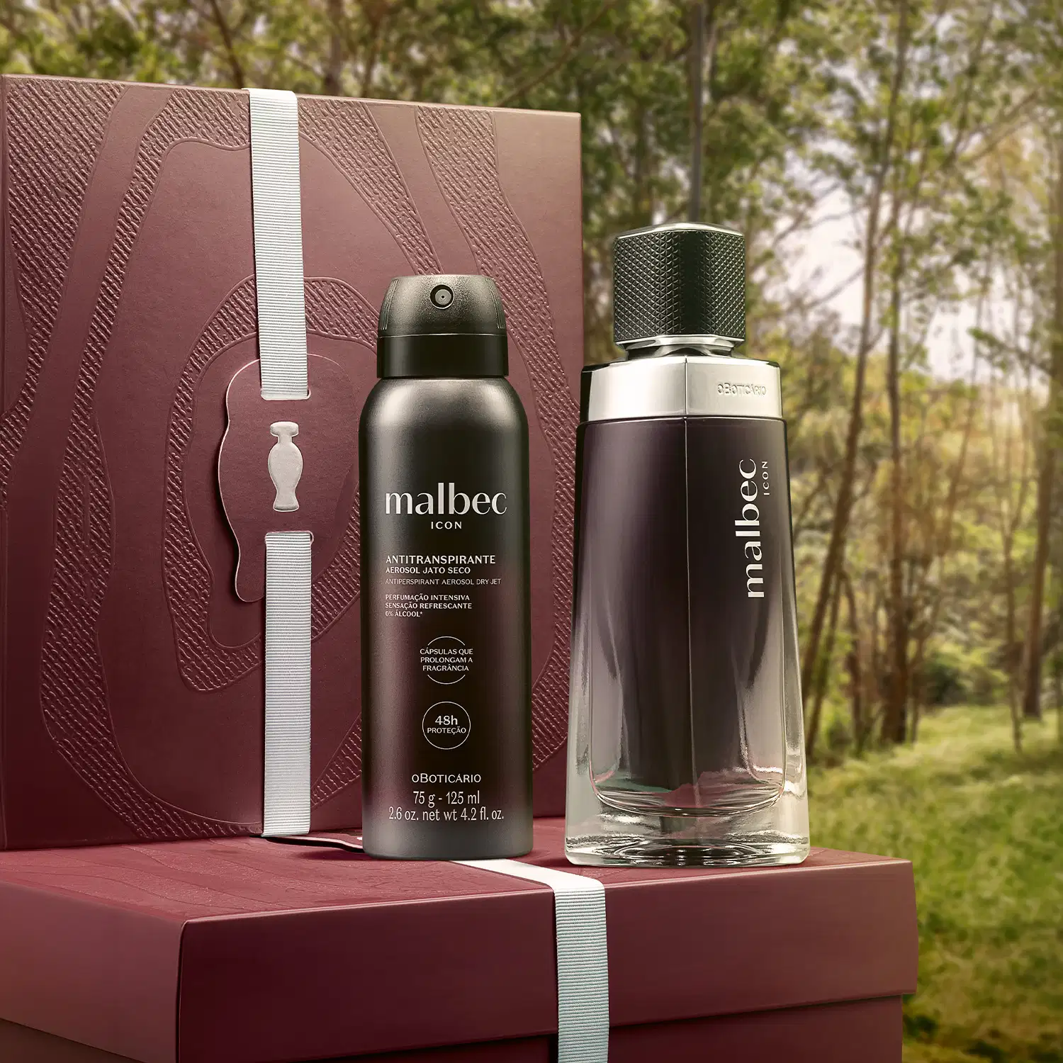 Caixa e embalagem de item de perfumaria da marca Malbec em primeiro plano, com fundo de floresta verde e árvores ao redor.