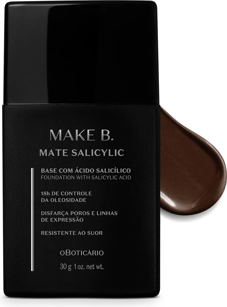 Frasco preto de base da linha Make B. Mate Salicylic com texto em branco trazendo informações do produto, como presença de ácido salicílico, controle de oleosidade e resistência ao suor. Atrás da embalagem, vemos um pouco de base marrom escuro espalhada.