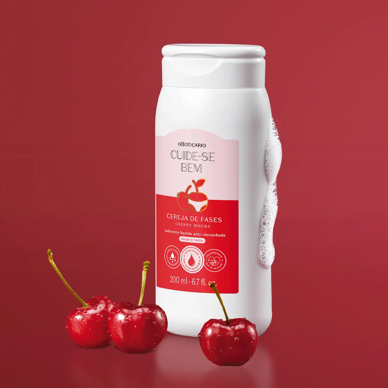 Imagem do recipiente branco do sabonete líquido com rótulo rosa e vermelho e imagem de cereja. Fundo vermelho com cerejas vermelhas frescas. Produto de cuidados pessoais com fragrância de cereja.