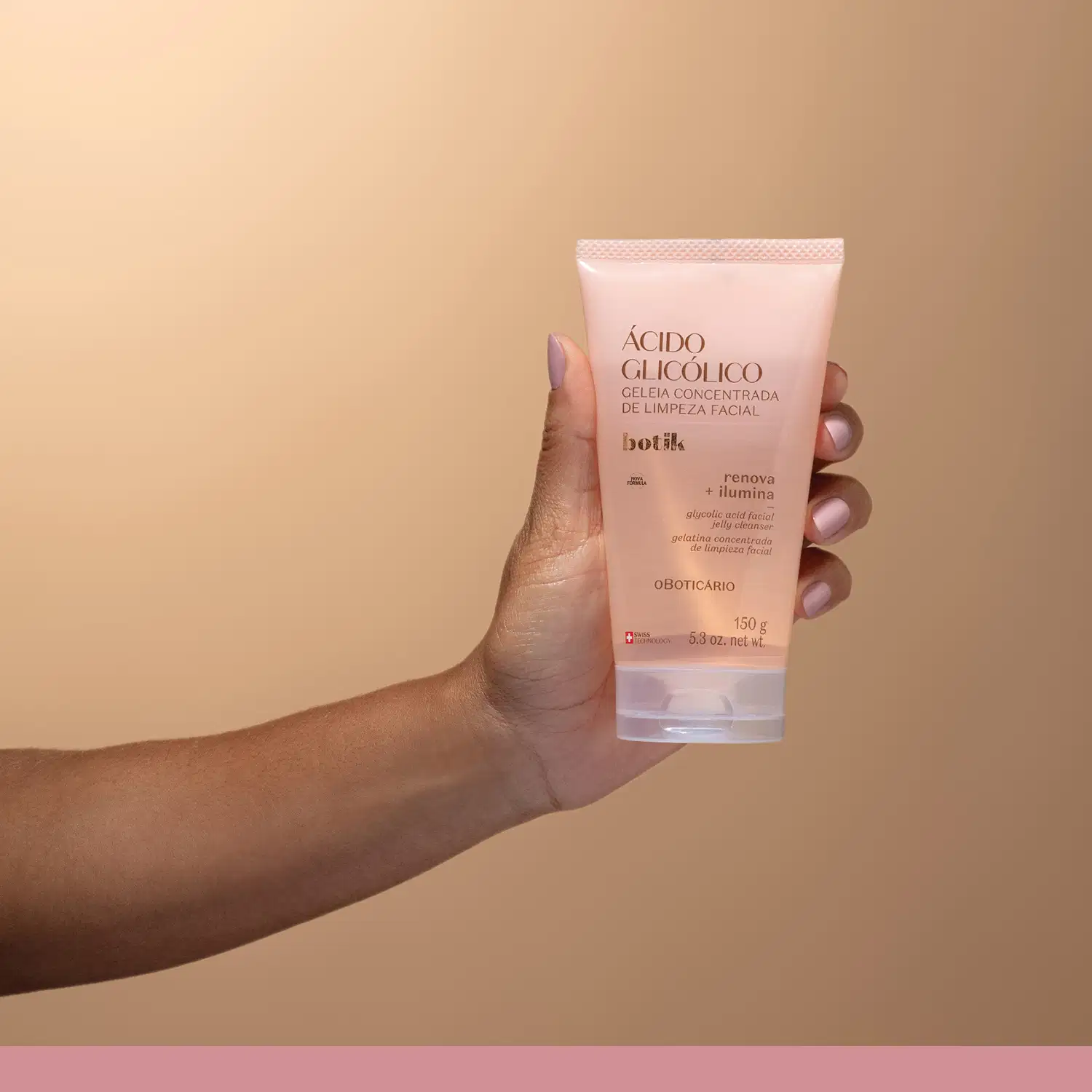 Tubo de gel de limpeza facial da marca Botik, sendo segurado por mão feminina de pele branca e unhas pintadas em cores claras contra fundo laranja claro, em ambiente simples e minimalista.