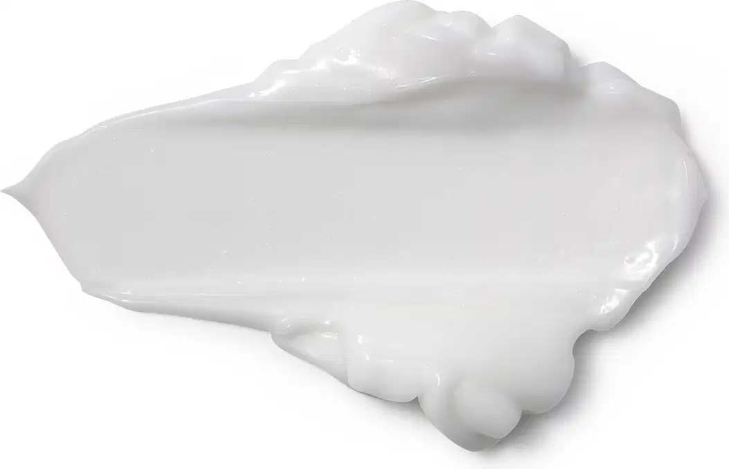 Textura branca e cremosa de produto de corpo e banho, com aspecto liso e brilhante, espalhada sobre superficie clara, ocupando grande parte da imagem.