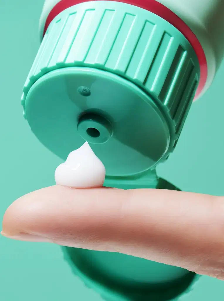 O produto de beleza apresenta uma textura cremosa e suave, com uma coloração verde clara e brilhante. Sua consistência parece ser leve e macia, com uma aparência uniforme e agradável.
