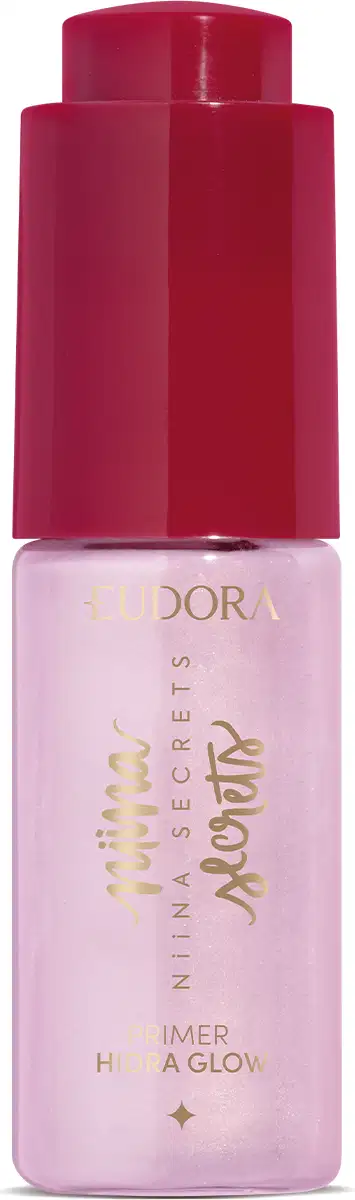 Embalagem cilíndrica de vido transparente e tampa plástica vermelha brilhante. Produto cor rosa claro brilhante. Na parte frontal do frasco rótulo transparente com letras douradas. Texto visível no rótulo: EUDORA Niina Secrets Primer Himer a Glow.