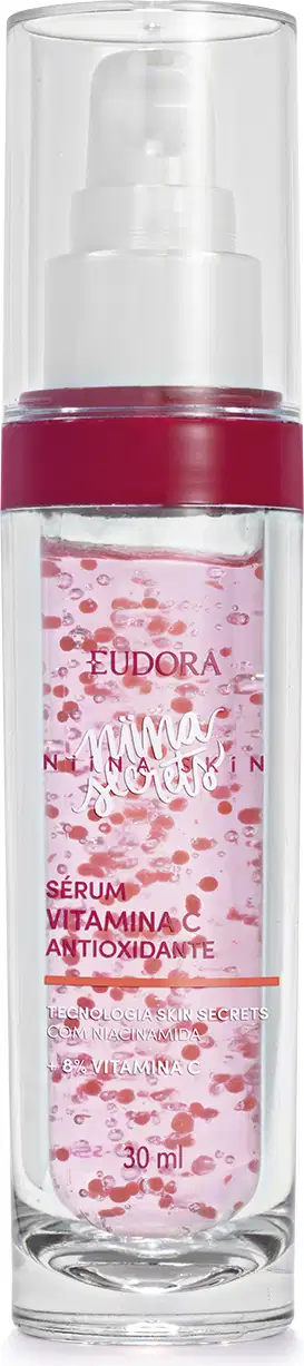Frasco cilíndrico de vidro transparente com tampa branca tipo pump e tampa protetora. Produto rosa claro contendo pequenos pontos vermelhos. Rótulo transparente em em letras brancas e rosa pink.