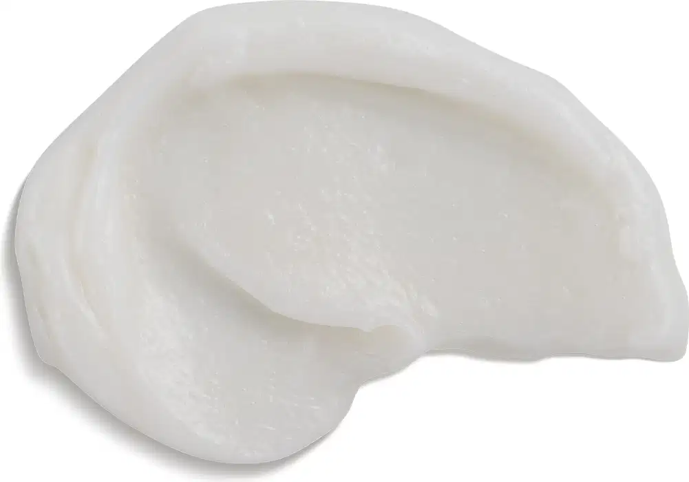 Produto com Consistência cremosa e cor branca. Forma arredondada e irregular, semelhante a uma concha ou pedra polida. Sem embalagem ou rótulos visíveis. Aparência simples e minimalista, focada na textura e forma orgânica do produto.