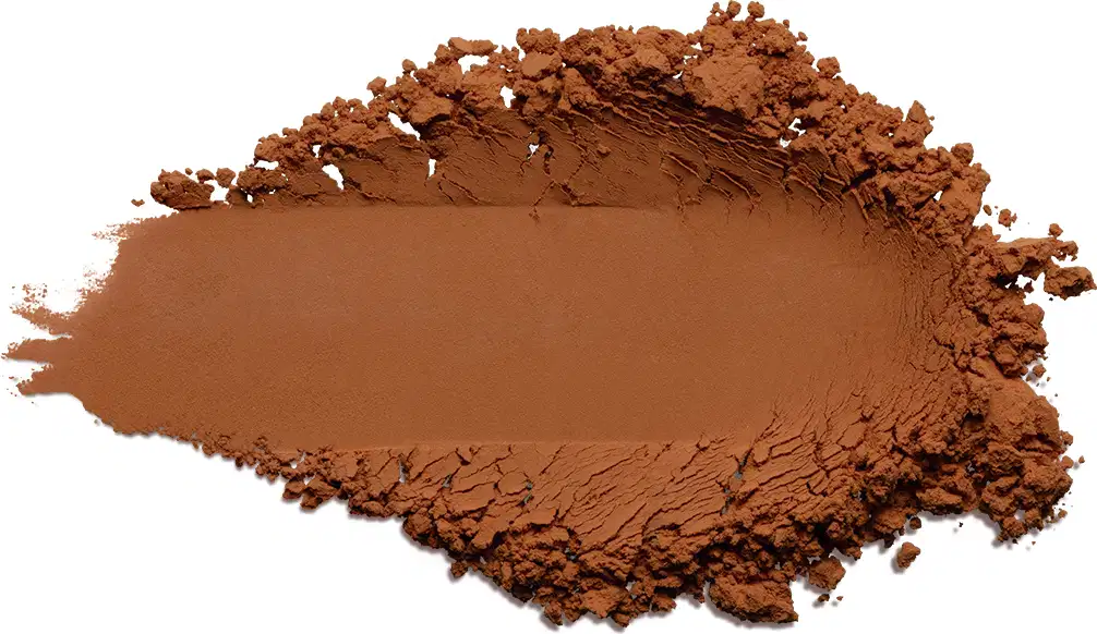 Pó compacto de cor 5 marrom terrosa vibrante. O produto apresenta uma textura fina e pulverizada, formando uma superfície irregular com pequenos montes de pó solto ao redor de uma área central mais compactada.