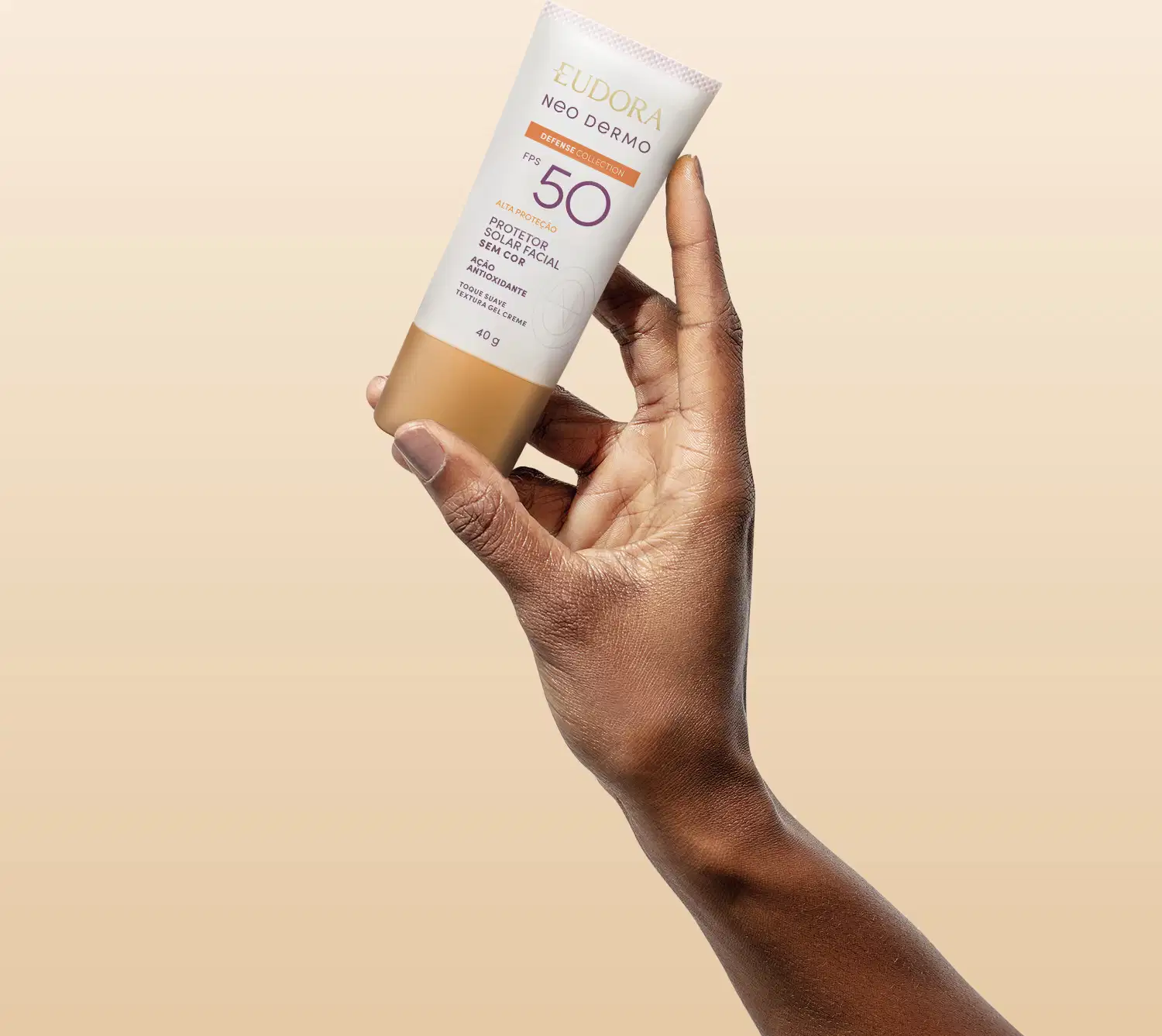 O produto mostrado está sendo segurado por uma mão, é um protetor solar Neo Dermo com FPS 50, em um tubo branco com detalhes roxo e laranja.