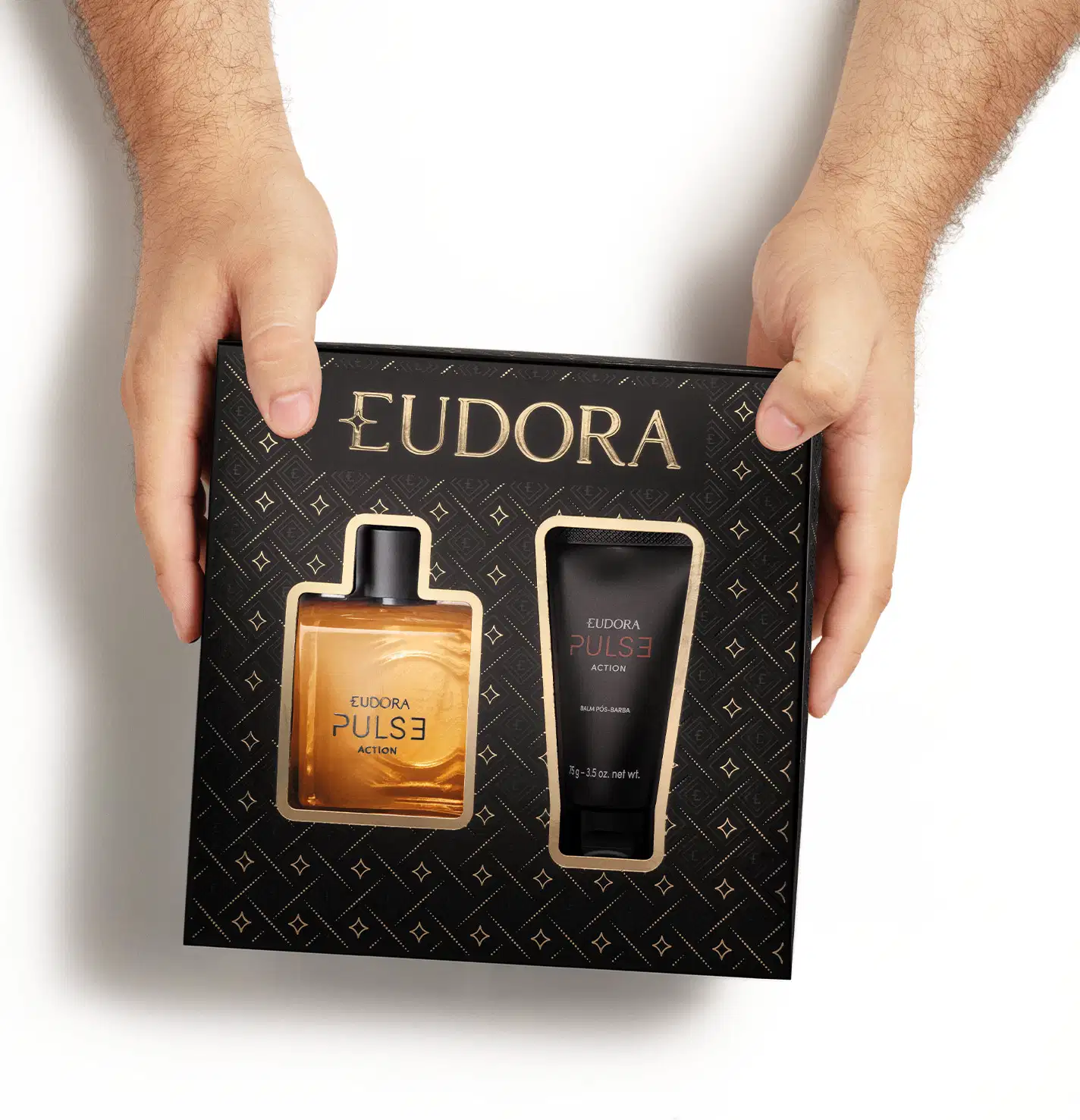 Caixa preta com o logotipo EUDORA e padrão geométrico repetido em dourado. Na sua parte frontal há a imagem do frasco de Eudora Pulse Action e do tubo do balm pós-barba.A caixa é vista de cima e é segurada pelos lados por duas mãos masculinas brancas.