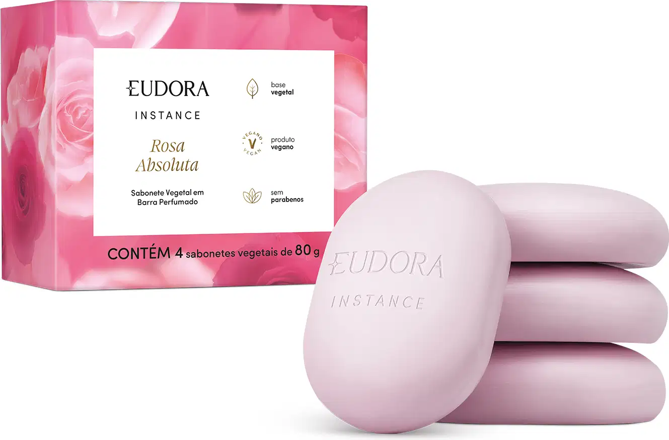 O produto apresentado é um conjunto de sabonetes vegetais da linha Instance Rosa Absoluta. A embalagem é uma caixa rosa com detalhes em branco, contendo 4 sabonetes vegetais de 80g cada. Os sabonetes em si possuem formato oval e coloração rosa clara.