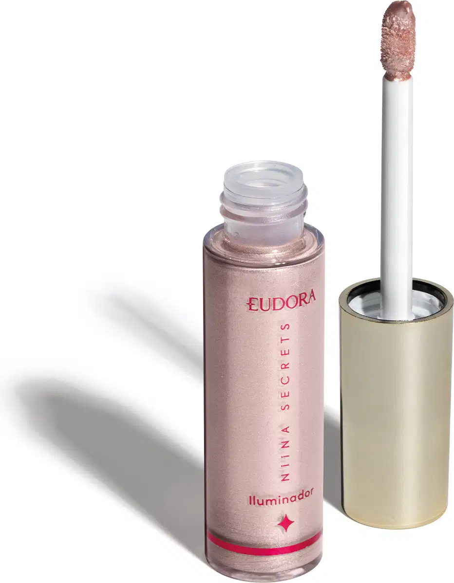 O produto apresentado é um iluminador da marca Eudora, da linha Niina Secrets. Trata-se de um frasco contendo um produto de cor rosé. O rótulo exibe o nome da marca "Eudora" e a descrição "Iluminador" em rosa. O aplicador é um pincel branco.