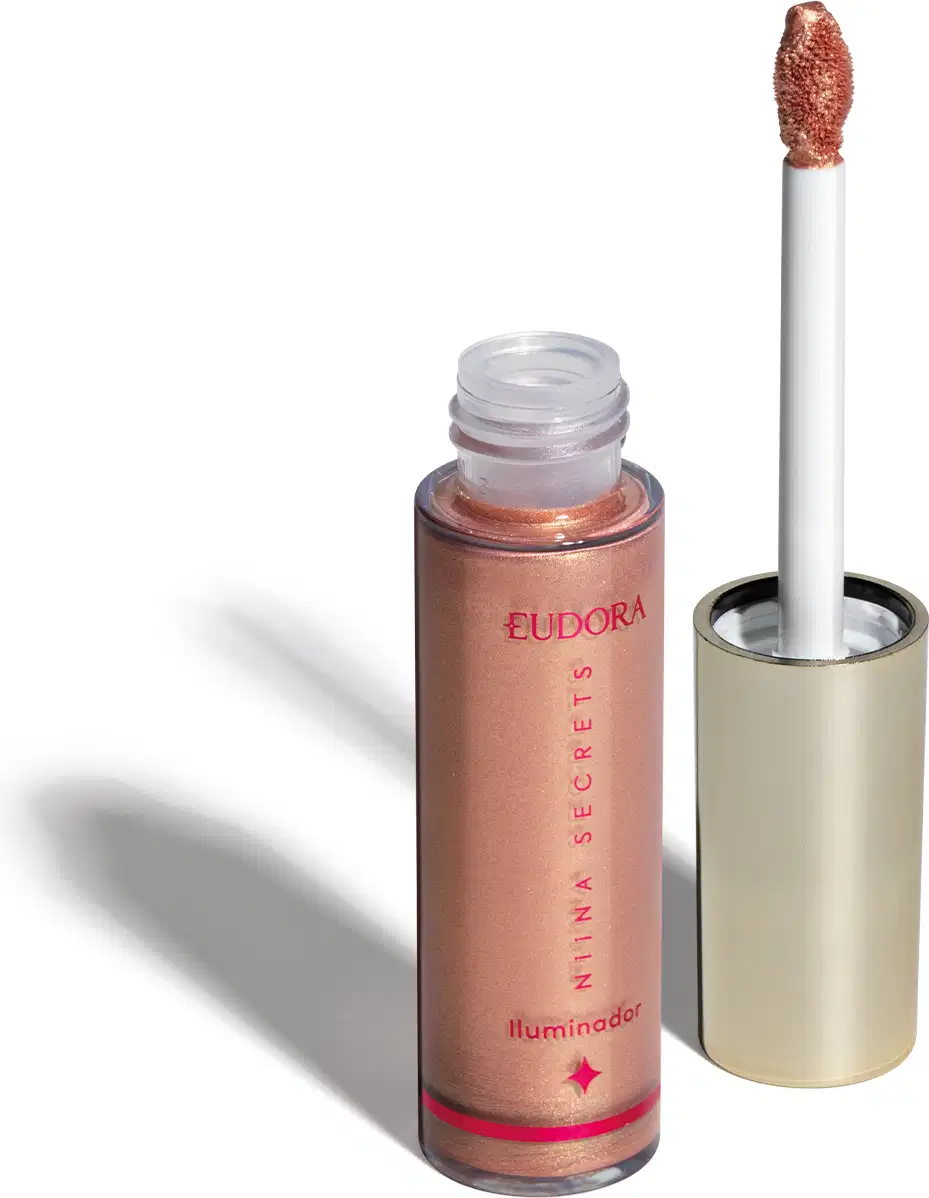 O produto apresentado é um iluminador da marca Eudora, da linha Niina Secrets. Trata-se de um frasco contendo um produto de cor bronzeada. O rótulo exibe o nome da marca "Eudora" e a descrição "Iluminador" em rosa. O aplicador é um pincel branco.