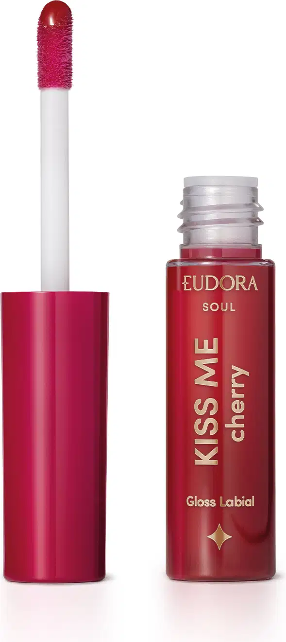 O produto mostrado na imagem é um gloss labial da linha Soul. A embalagem é um tubo plástico vermelho com o nome "Kiss me cherry" impresso. O aplicador do gloss é de cor rosa vibrante.