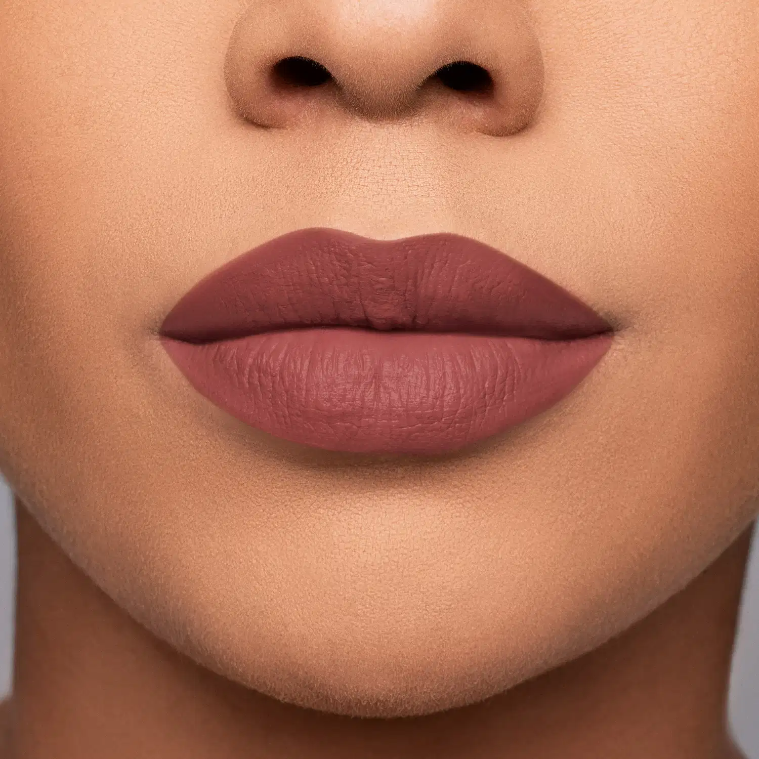 Imagem de close-up de lábios femininos com maquiagem em tom rosado, sugerindo um produto de beleza da marca.