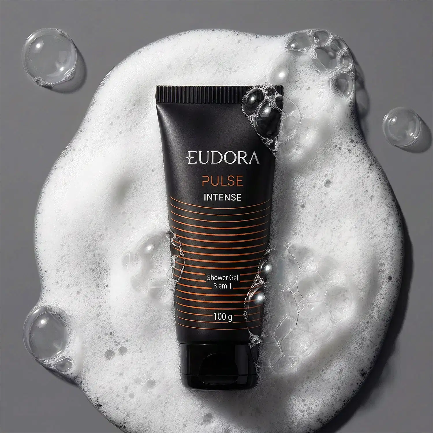 Imagem mostra um tubo de gel de banho da marca Eudora, com a linha "Pulse Intense", com a textura de bolhas de sabão e espuma ao fundo, sugerindo um contexto de higiene e cuidados pessoais.