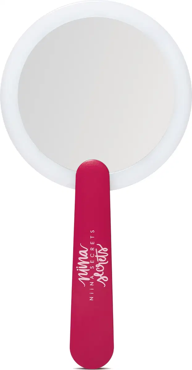 O produto apresentado é um espelho de mão da marca Niina Secrets. Possui um formato circular com um acabamento branco. O cabo do espelho é de cor rosa vibrante, com o nome da marca impresso em letras brancas.