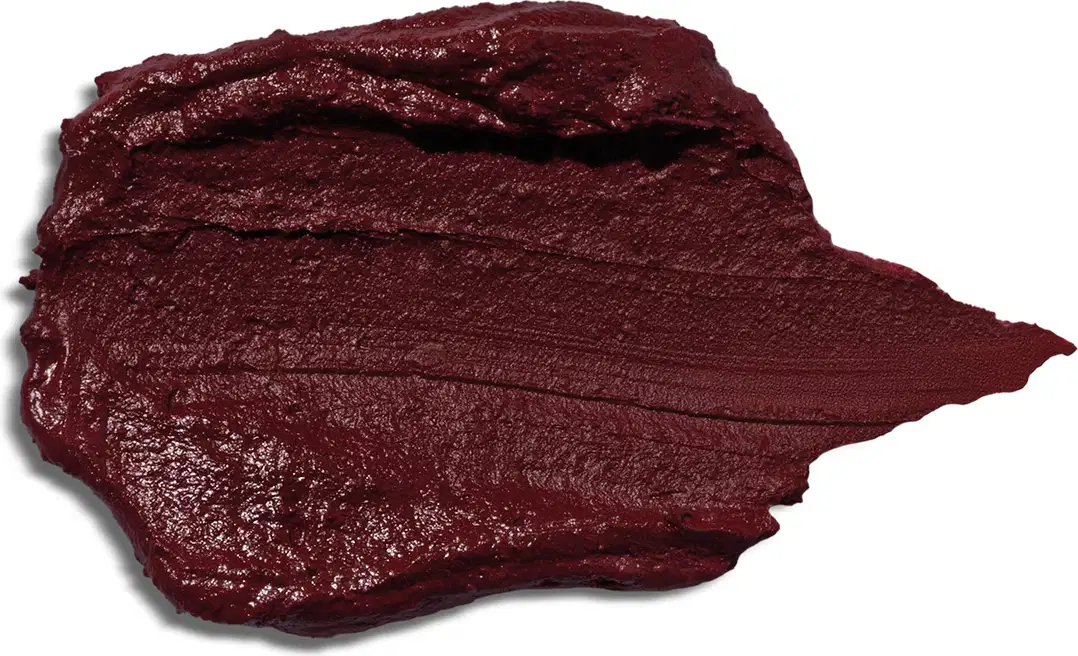 Textura do Blush Stick, com uma consistência cremosa e pigmentação intensa. De cor vinho escuro. Na imagem não mostra nenhuma embalagem ou outras informações.
