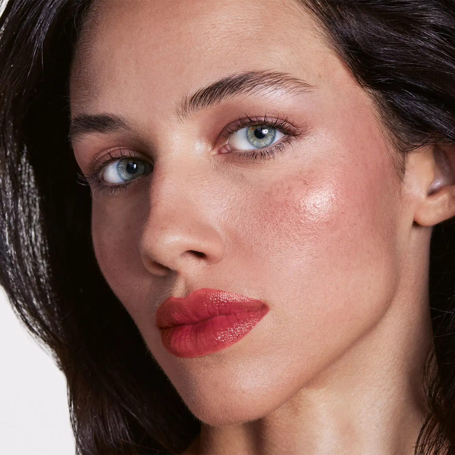 Close no rosto de uma mulher branca com a aplicação do produto nos lábios.
