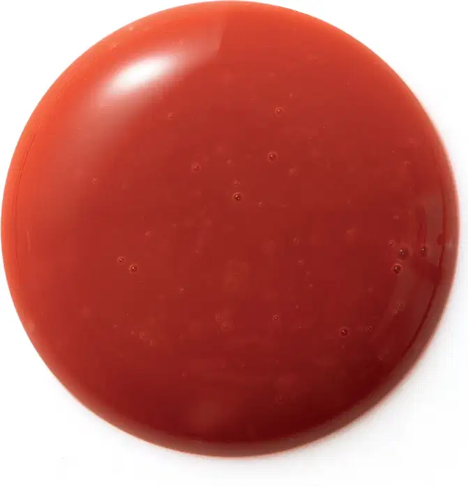 Textura cremosa, brilhante e uniforme em tom vermelho intenso, com aparência lisa e suave ao toque, típica de um produto de beleza da linha Eudora Make.