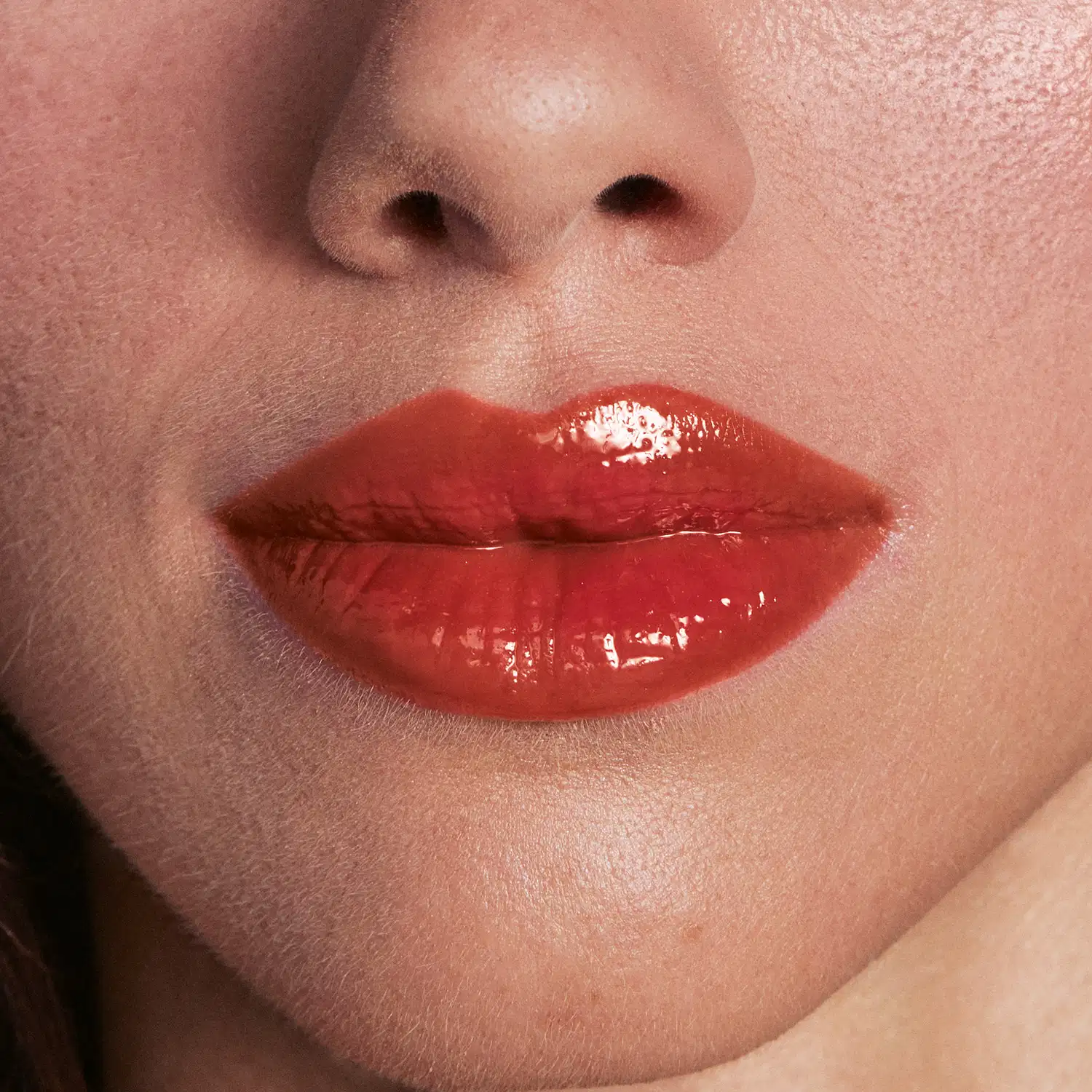 Imagem de close-up de lábios femininos com batom vermelho brilhante, sugerindo um produto de maquiagem de alta qualidade e acabamento luxuoso.