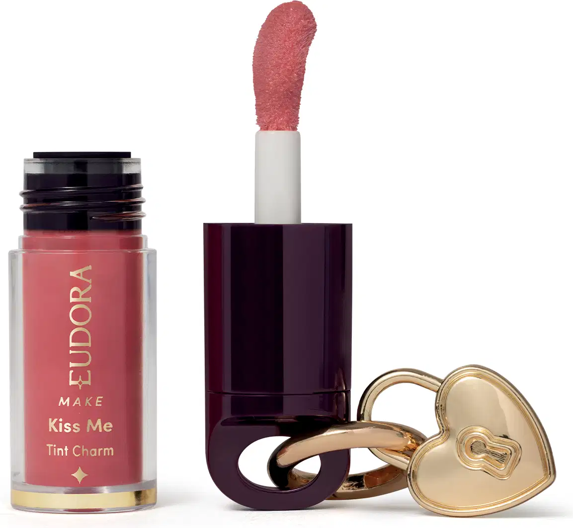 O produto de beleza Eudora Make apresenta um batom líquido rosa em embalagem cilíndrica, acompanhado de um espelho compacto dourado em formato de coração.
