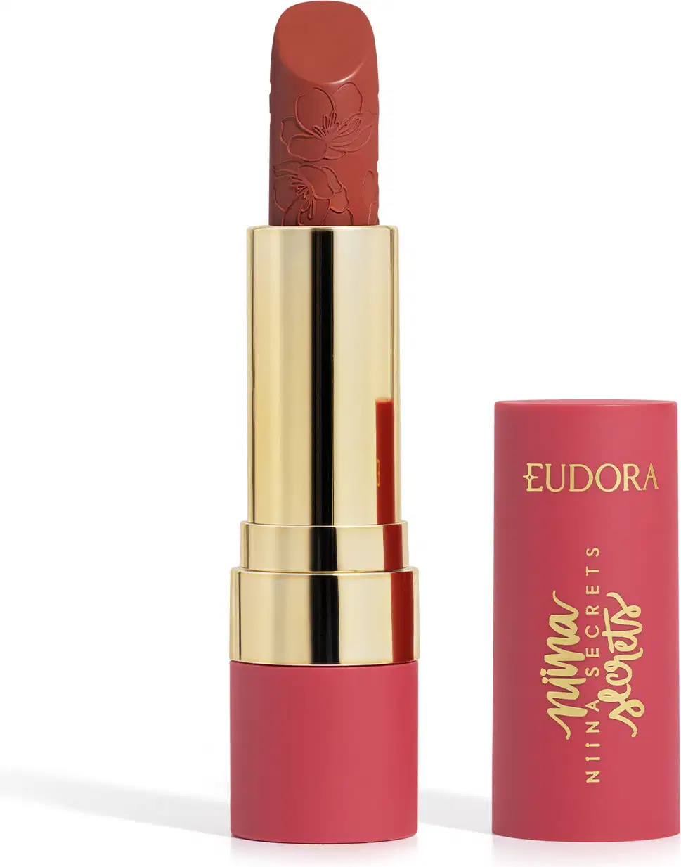 Embalagem de um batom aberto, com corpo dourado e tampa e base rosa, escrito "Eudora Niina Secrets". A cor do batom é vermelha e tem um relevo exclusivo em padrão floral na bala. Produto de beleza com design elegante e sofisticado.
