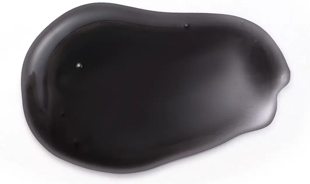 Textura escura, brilhante e viscosa de um item de um produto para cabelos da marca Siàge, em uma superfície clara.