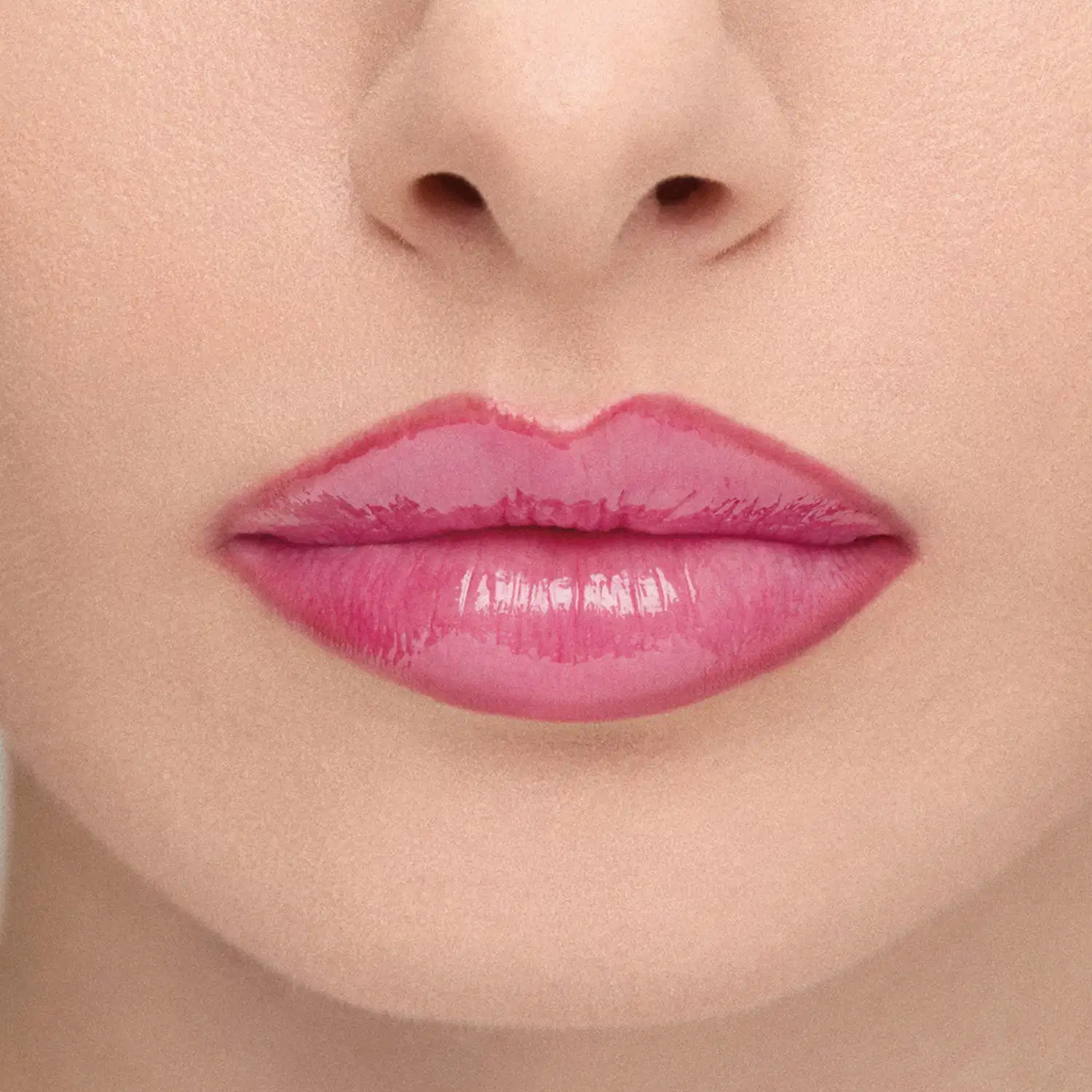 Imagem em close-up dos lábios de uma modelo, mostrando o efeito do Gloss: Lábios rosados com brilho, em primeiro plano, sobre fundo neutro.
