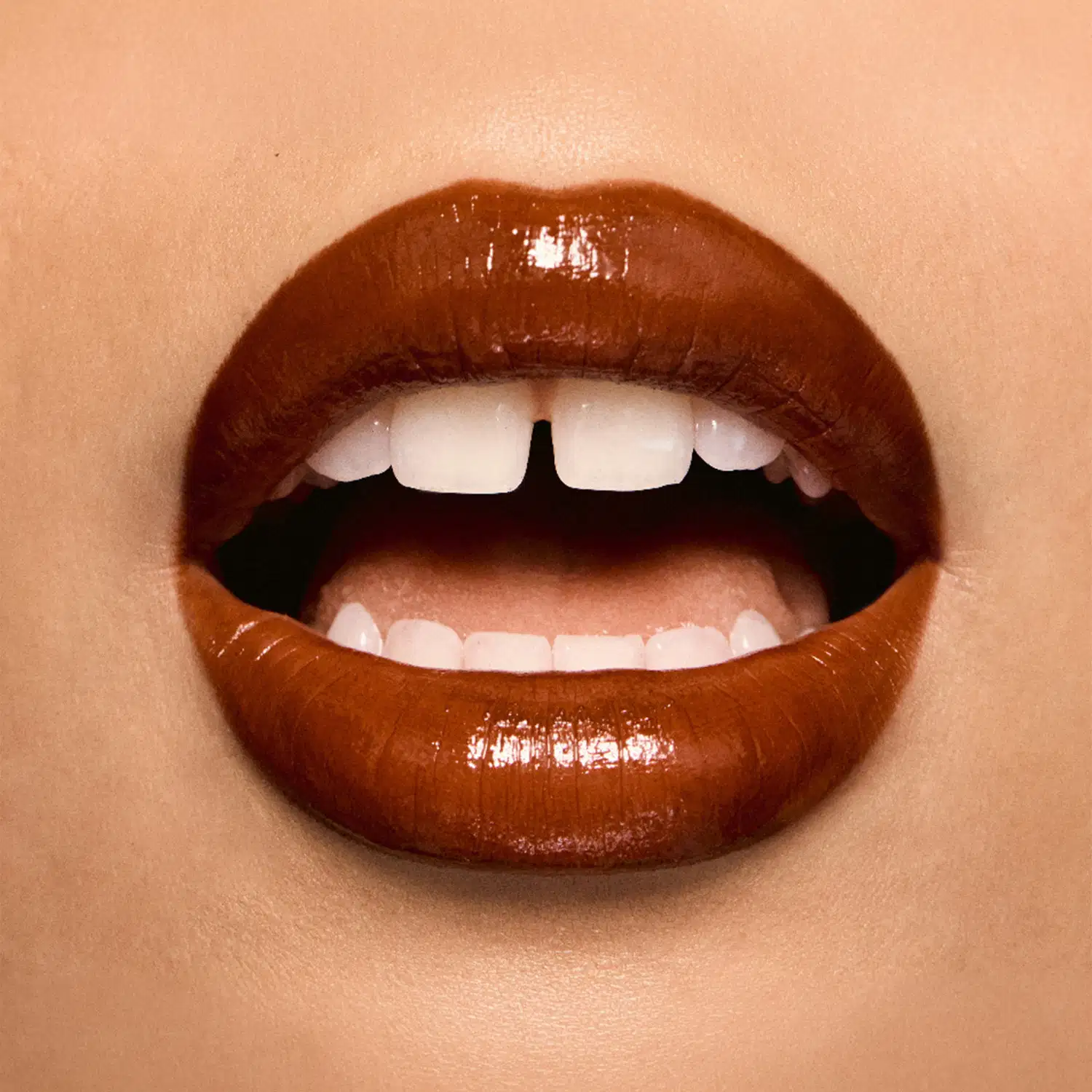 Imagem em close de lábios com batom canela em tom brilhante e glossy em primeiro plano.

