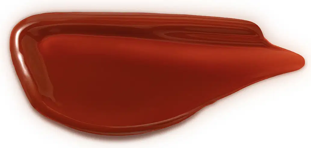 Textura de produto de maquiagem em tom canela, com acabamento brilhante e consistência cremosa, exibida em superfície plana.