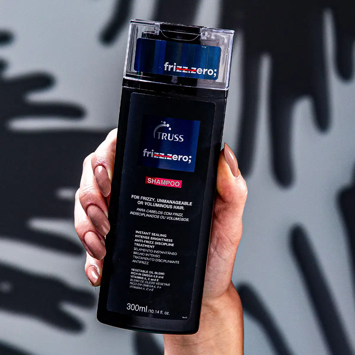 A imagem mostra um frasco de shampoo da marca Frizz.zero da linha Truss. O frasco é retangular, com um design moderno e simples. A embalagem apresenta o nome da marca em letras claras e destaca que é um shampoo para cabelos frizados ou volumosos.