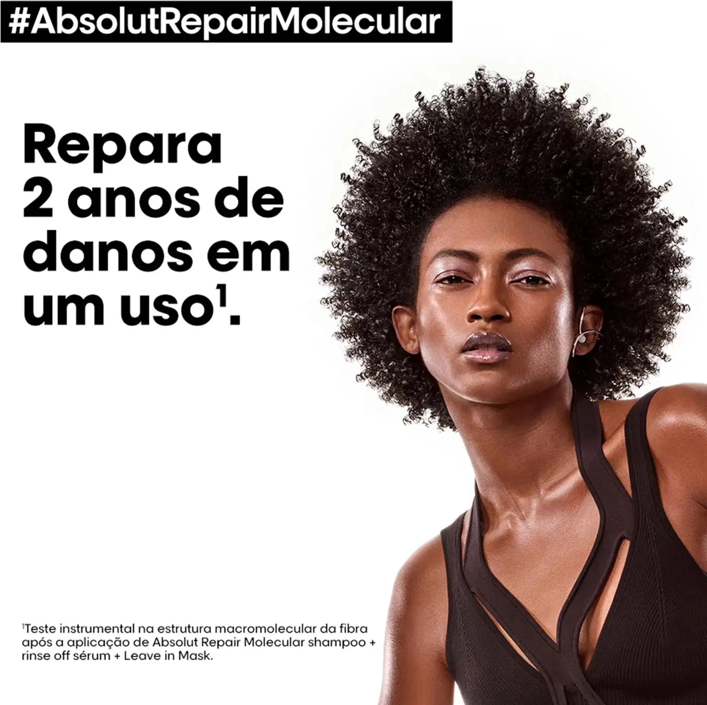 A imagem apresenta uma mulher afro-brasileira com cabelos crespos e volumosos, em um ambiente de divulgação de um produto de tratamento capilar da marca L'Oréal Professionnel, com destaque para o texto "#AbsolutRepairMolecular".