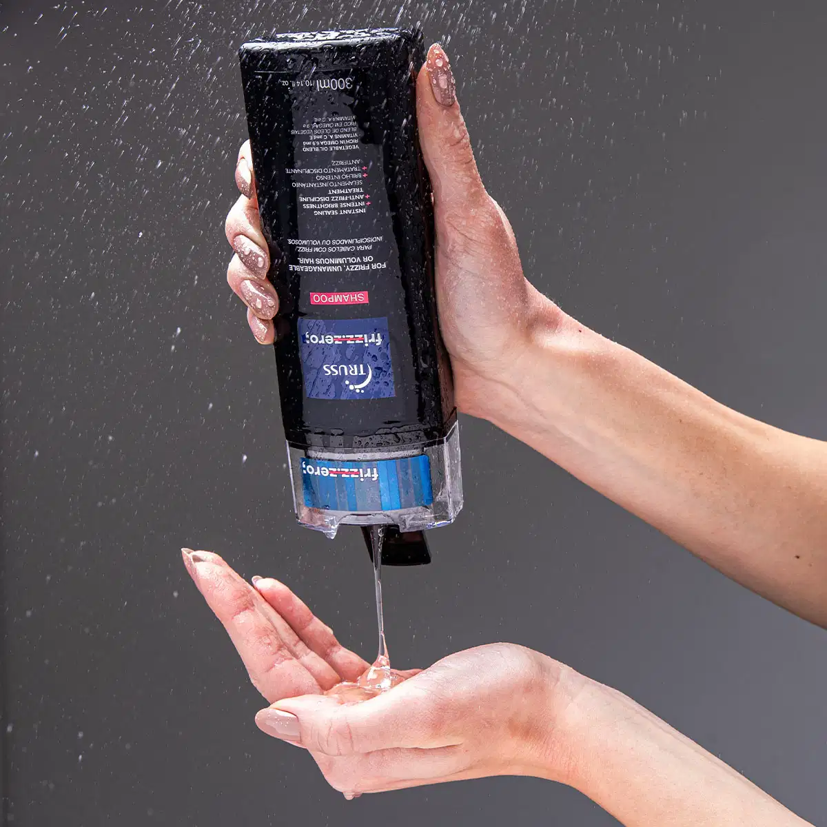 Shampoo da marca Truss. Frasco plástico preto retangular com rótulos azuis e vermelhos. O líquido está sendo despejado do frasco em uma mão aberta, com gotas caindo.