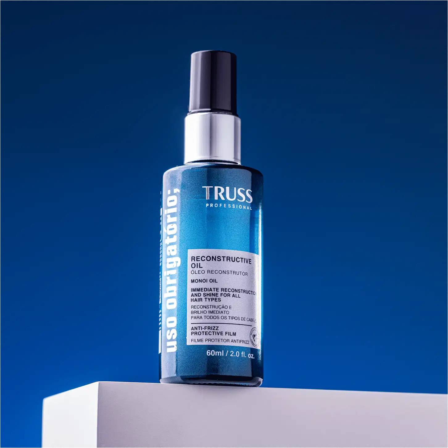 A imagem mostra o frasco do óleo Uso Obrigatório, sua embalagem é azul cilíndrica com tampa em spray.