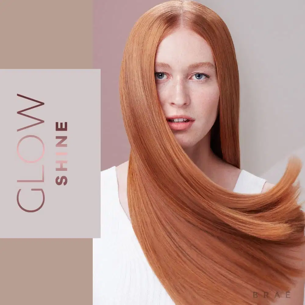 A imagem mostra uma modelo com longos cabelos lisos e brilhantes em um tom de ruivo intenso e uniforme. Ela usa uma blusa branca e tem uma expressão séria. Ao lado, há um painel com o logotipo "Glow Shine" em letras marrons sobre fundo bege claro.