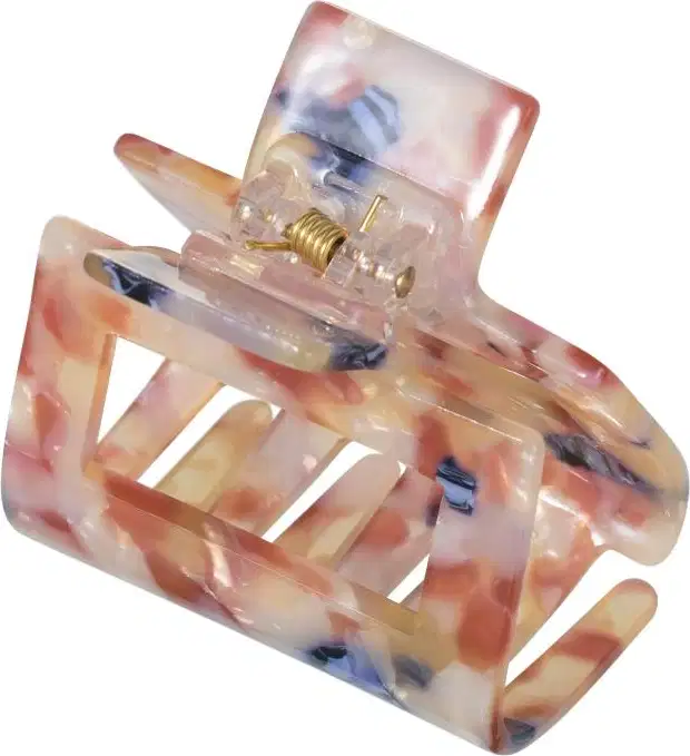 A imagem mostra piranha de cabelo feita de material plástico acrílico. Possui uma forma ondulada e irregular, com cavidades e relevos. A peça apresenta uma coloração predominantemente rosa claro, com manchas em tons de azul e bege.