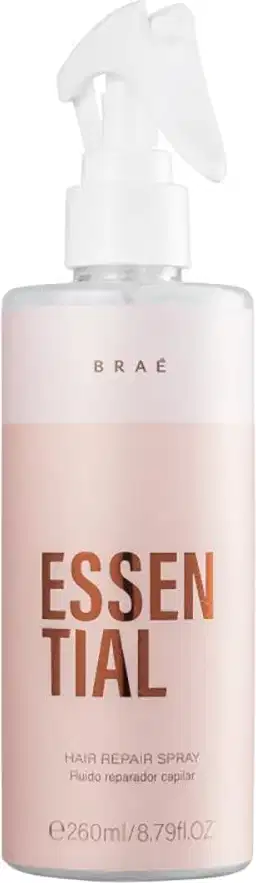 Produto de reparação capilar em spray da marca Braé. Embalagem plástica na cor rosa claro. Rótulo com o nome do produto "Essential" em letras marrons grandes e a descrição "Hair Repair Spray" em letras menores.