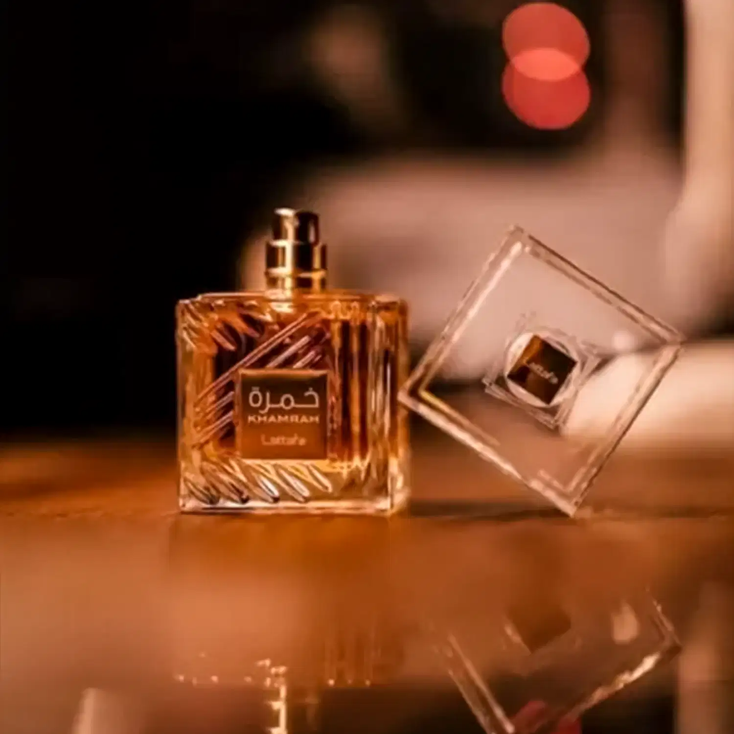 Dois frascos de item de perfumaria da marca Khambrah, com embalagens de vidro transparente e dourada, exibindo o nome da marca em árabe e em inglês.