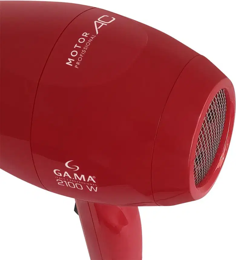 A imagem mostra o fundo do secador de cabelo da marca GA.MA Italy. O produto tem uma carcaça vermelha brilhante. A parte traseira possui uma grade metálica protetora para a saída de ar quente. O formato é cilíndrico e alongado.
