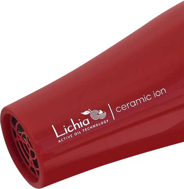 A imagem mostra a ponta do secador. O corpo é cilíndrico, vermelho e traz uma grade vazada na saída de ar. Na lateral possui o logotipo e nome da marca "Lichia Ceramic Active Oil Technology" impresso em letras brancas.