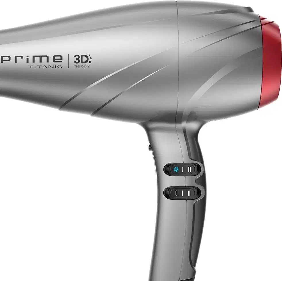 A imagem traz o secador de cabelo da GA.MA Italy Prime 3D Titanio. O acessório possui um corpo alongado e aerodinâmico em plástico cinza e detalhes em vermelho. O cabo traz dois botões par ajustar a temperatura e a velocidade do acessório.