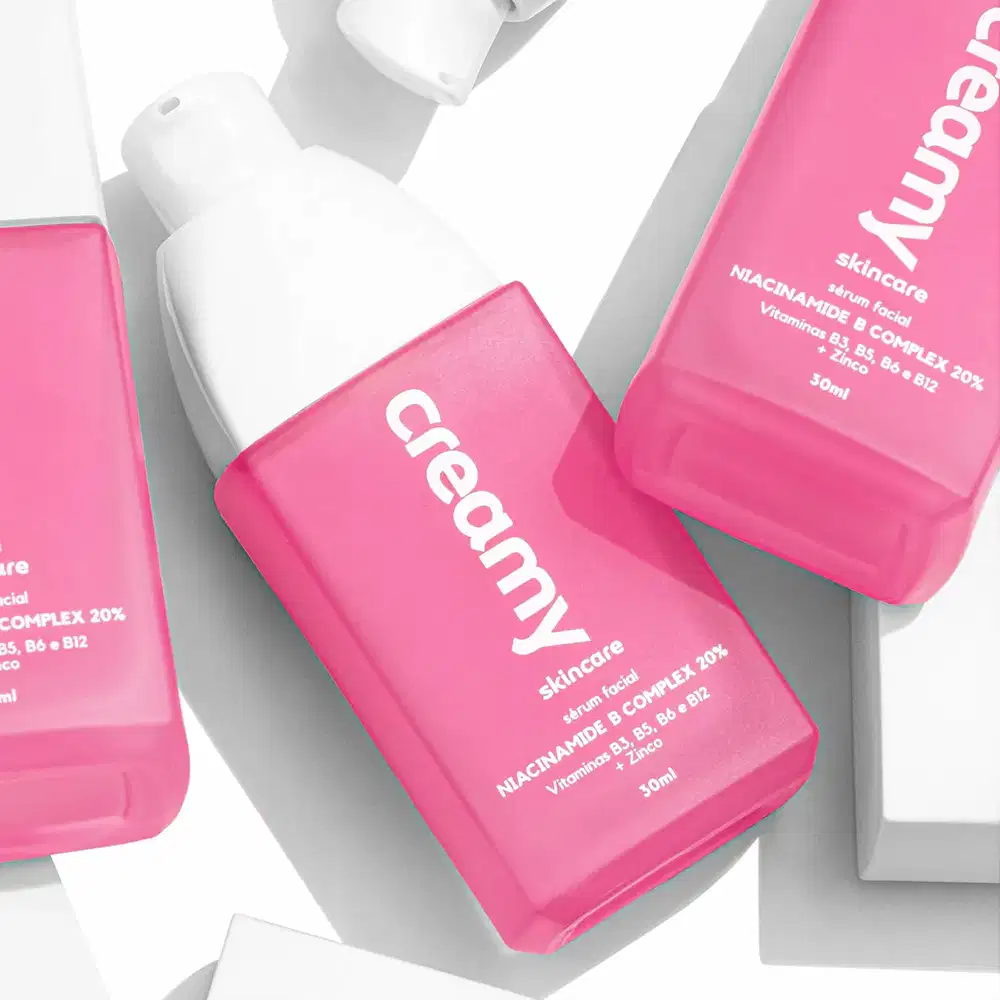 A imagem mostra dois frascos retangulares transparentes do produto cor rosa e tampa branca.