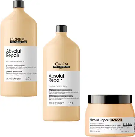 A imagem mostra três produtos da linha Absolut Repair da L'Oréal Professionnel. Dois frascos de 1,5 litros de shampoo e condicionador com proteína e quinoa dourada. Um terceiro produto é uma máscara profissional em um pote plástico bege com tampa preta.