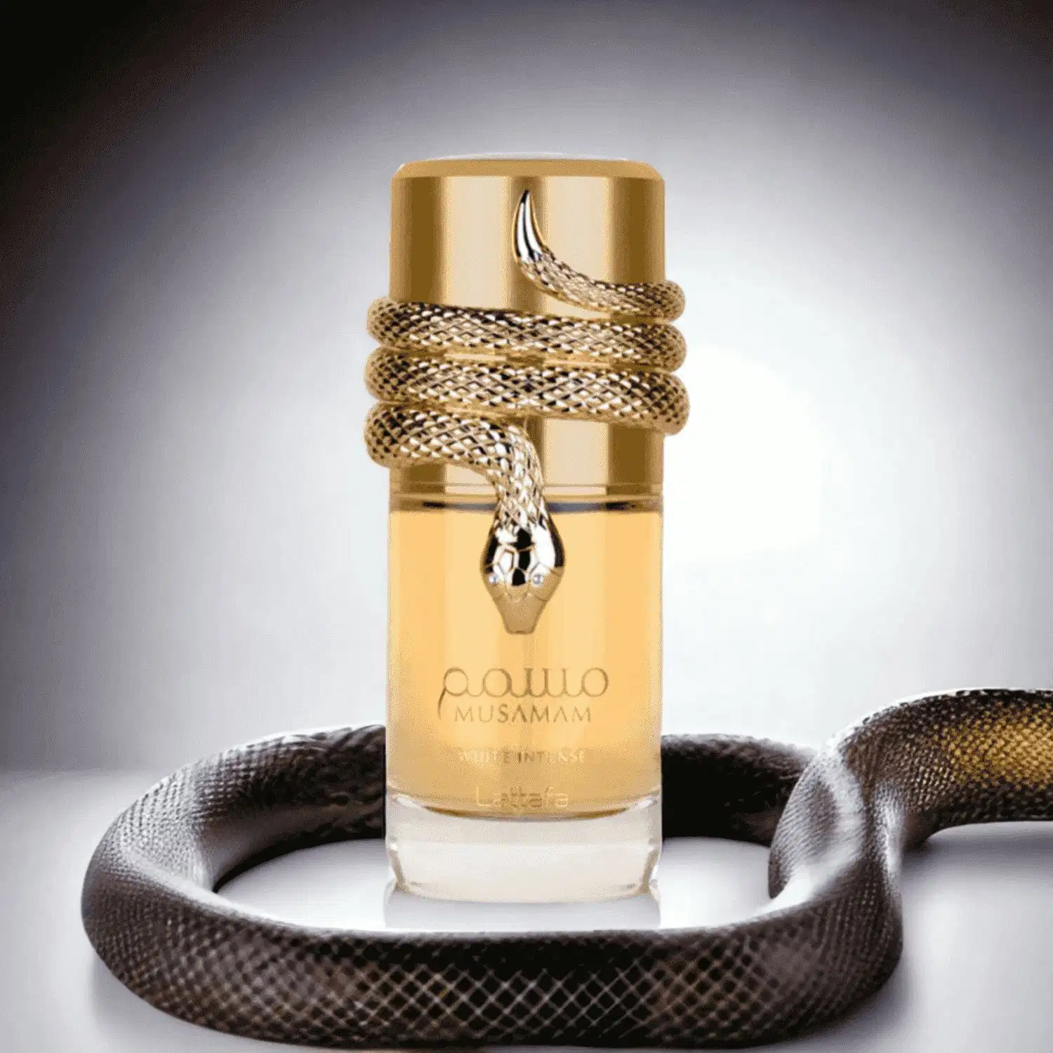 Recipiente de item de perfumaria dourado com cobra enrolada em volta, em ambiente escuro com tecido de textura próximo. Produto da marca Musamam em destaque.