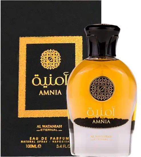 Perfume Amnia da marca Al Wataniah. Frasco de vidro âmbar com tampa preta brilhante. Caixa preta com detalhes dourados e o logotipo da marca em arabescos. Rótulo no frasco com o nome "Amnia" e detalhes em árabe.
