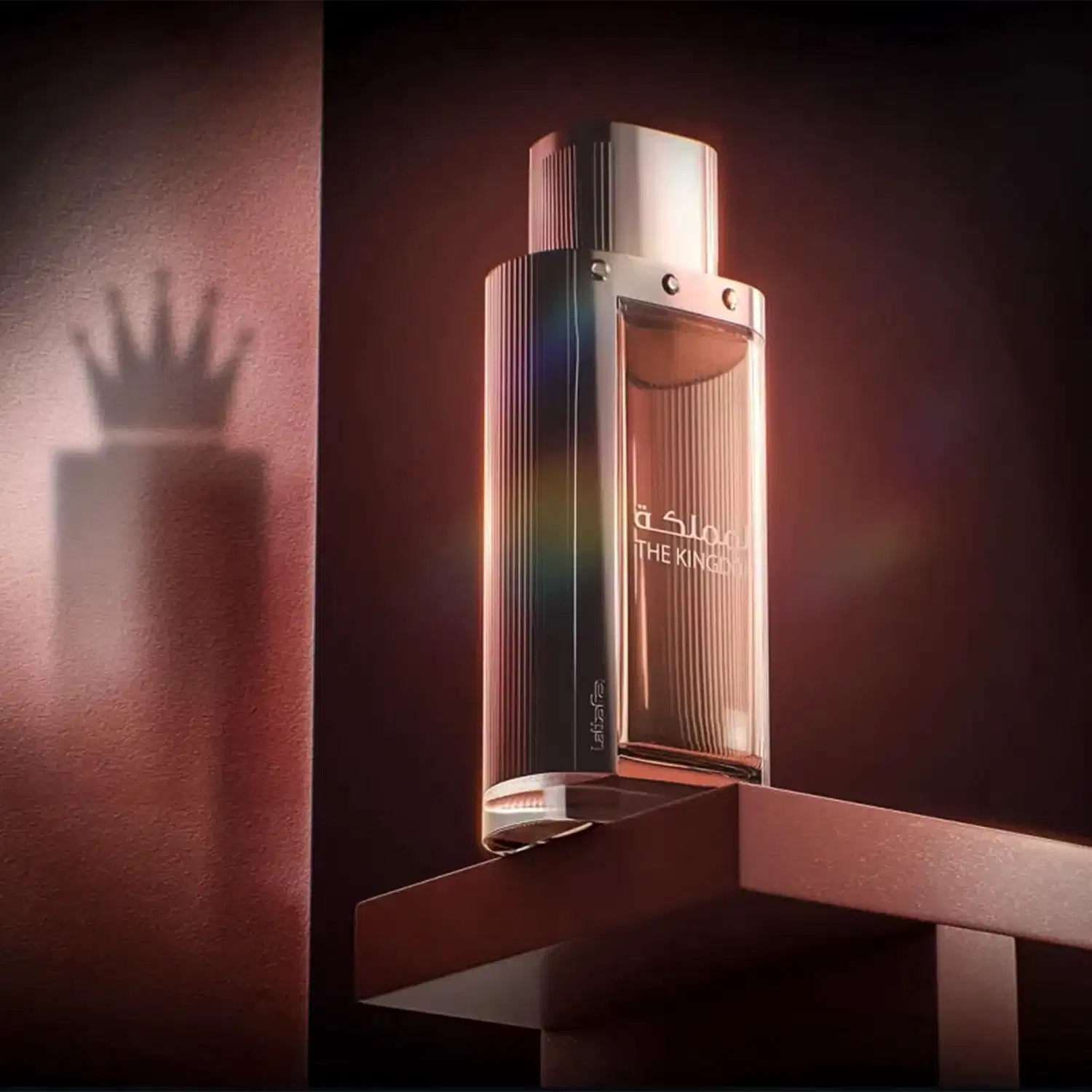 Ambiente escuro e elegante, com iluminação suave, destacando um frasco de perfume da marca Lattafa Perfumes, intitulado "The Kingdom". O produto é o foco central, sugerindo um contexto de luxo e sofisticação.