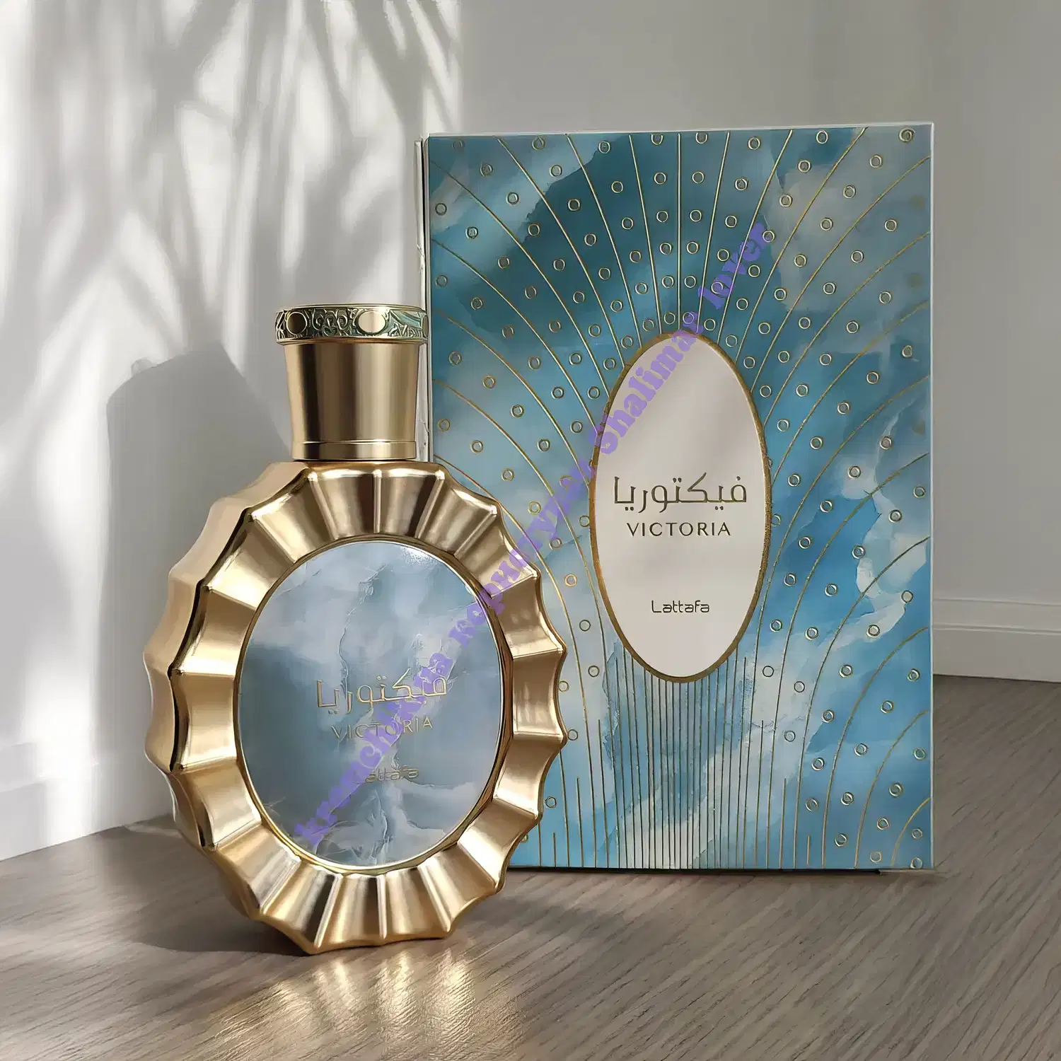 Recipiente dourado de item de perfumaria com formato oval e detalhes decorativos. Caixa azul com padrão de círculos e texto "Victoria" em destaque. Embalagem com design elegante e sofisticado.